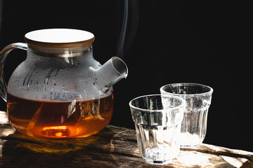 The steam from a cup or pot of coffee or tea on the old wood table and black background, Warm drinks make good healthy, Selective focus.