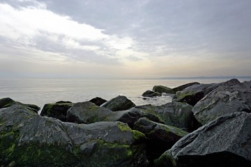 Seascape view from the beach with large mossy stones.