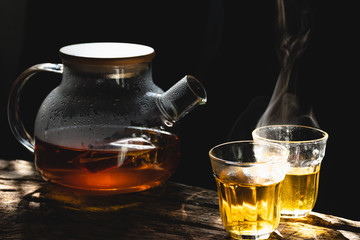 The steam from a cup or pot of coffee or tea on the old wood table and black background, Warm drinks make good healthy, Selective focus.
