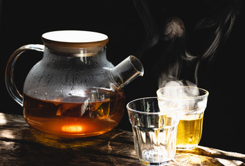 The steam from a cup or pot of coffee or tea on the old wood table and black background, Warm drinks make good healthy, Selective focus.