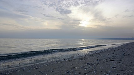 Wavy seascape view from the beach with pebbles and seashells on it.