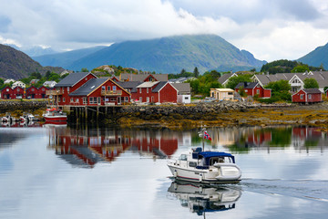 A tourist boat runs on the water at Ballstad Lofoten Island, Norway.