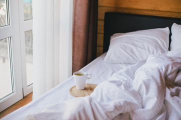 Cup of green tea in bed in cozy wooden house.