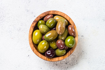 Olives in wooden bowl on white background.