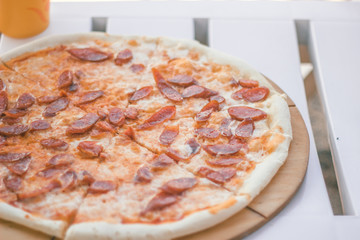 Close-up whole pizza with sausages and cheese. Beach food.