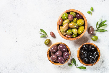 Natural greek Olives in wooden bowls and olive oil bottle on white background.