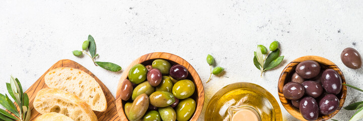 Olives, ciabatta and olive oil on white background.