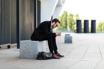 Modern young man playing on phone, browsing mobile news. Gadget Dependence.