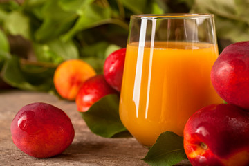 Glass of nectarine juice with fresh nectarines on rustic background