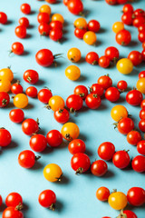 Red and yellow cherry tomatoes on blue background. Fresh bright organic vegetables.