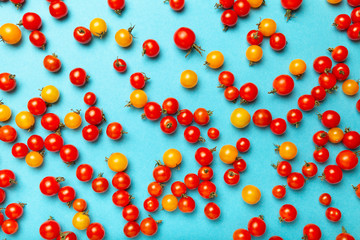 Red and yellow cherry tomatoes on blue background. Fresh bright organic vegetables.