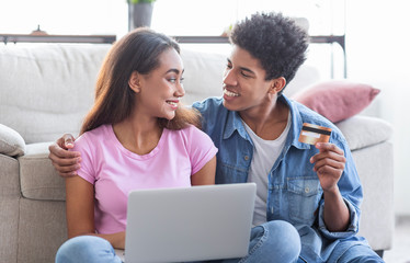 Young african couple shopping online, using laptop and credit card