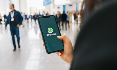 WhatsApp Business BERLIN, GERMANY AUGUST 2019: Woman holding a iPhone Xs opening Whatsapp app on a conference. WhatsApp messenger for sending messages via the Internet.