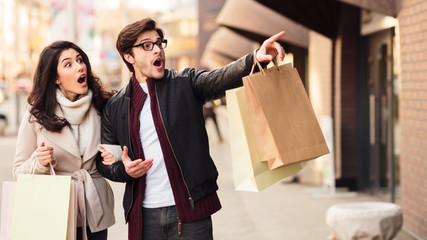 Guy pointing on shopwindow, walking and shopping outdoors