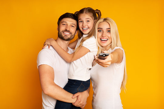 Happy Parents And Daughter Switching Channels Watching TV, Studio Shot