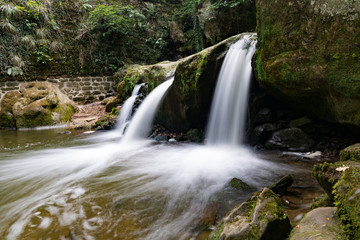 Fototapeta na wymiar idyllic small waterfall in lush green forest landscape