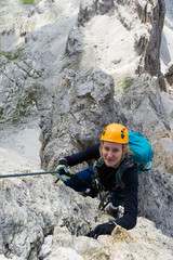 attractive blonde female climber on a steep Via Ferrata in the Italian Dolomites