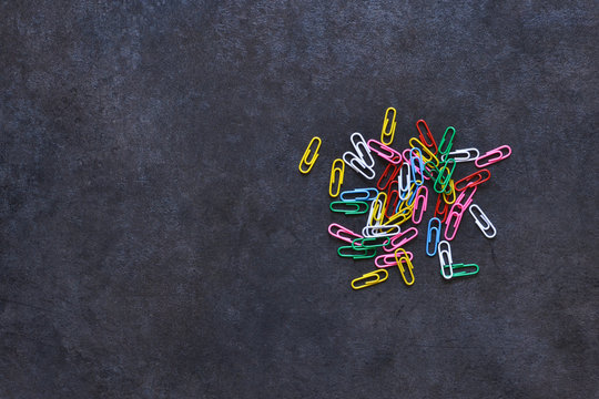 Set of multi-colored paper clips on a black background.