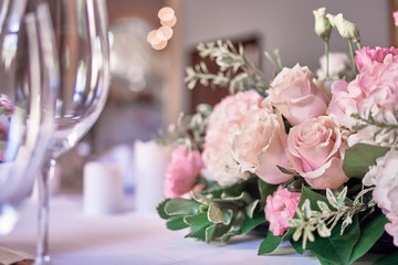 Bouquet on the table. Wine glasses in the foreground. Wedding Banquet or gala dinner. The chairs and table for guests, served with cutlery and crockery.