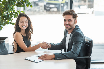 beautiful young woman manager shaking hands with handsome man client after holding succesful business purchase deal at the office