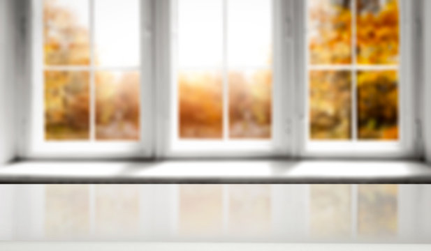 Wooden table of free space for your decorationa and white wooden window space with autumn landscape 