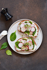 Bread toast with cheese, spinach, radish and cress on the kitchen table. View from above.