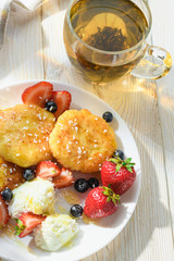 cheesecakes with honey tea and berries on a wooden table