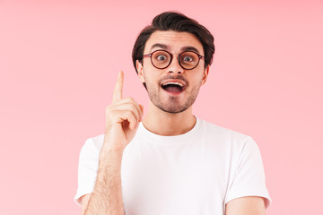 Image of brunette amazed man wearing eyeglasses pointing finger upward at copyspace