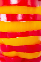 red and yellow bell pepper cut half into pieces on white background, top view.