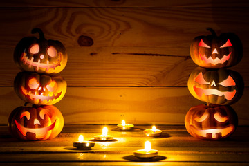 Six Scary Halloween pumpkins on a wooden background with space for text. Halloween card concept. Spooky glowing faces with candlelight.