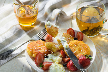cheesecakes with honey tea and berries on a wooden table