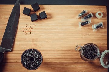 Hookah making on a wooden board and accessories. Hookah bowl and tobacco.