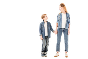 Fototapeta premium full length view of happy mother and son holding hands and looking at each other isolated on white