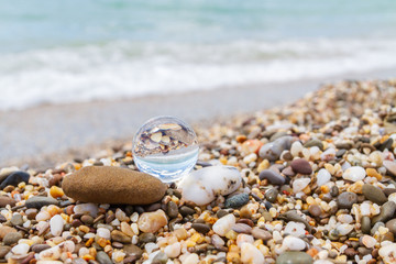 Glass round ball on the beach reflects the sea in summer