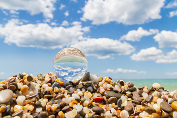 Glass round ball on the beach reflects the sea in summer