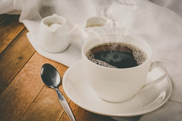 a cup of coffee, milk and sugar on wooden table, vintage tone