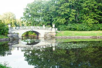 Fototapeta na wymiar old vintage bridge on river in green park, landscape historical
