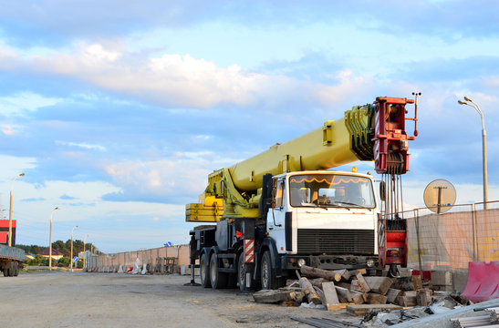 Unloading of cargo and building materials by mobile truck crane at the construction site. Auto crane during the construction of a bridge and highway road - Image