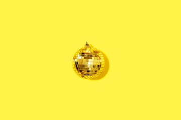 Creative Christmas composition. Flat lay, top view. Disco ball bauble on yellow background with copy space. Minimal New year party concept. Minimal Christmas gold decoration