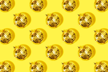 Creative Christmas pattern. Shiny gold disco balls over yellow background. Flat lay, top view. New year baubles, star sparkles. Party time. Cristmas greeting card