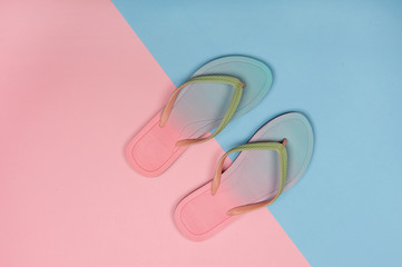 Stylish beach flip-flops on pink and blue pastel background, top view. Summer minimalism concept with copy space.
