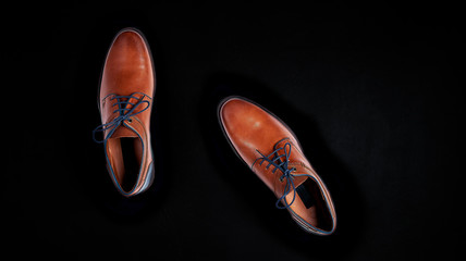 Background for sale black friday, luxurious male brown and blue leather shoes isolated on a black background , top view