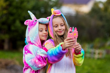 Girlfriends in unicorn costumes. Party unicorns. Two girlfriends take a selfie on the phone.