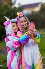 Girlfriends in unicorn costumes. Party unicorns. Two girlfriends take a selfie on the phone. © viclin