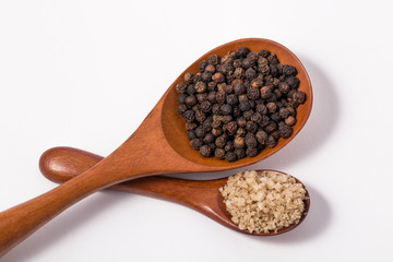 Sea salt and whole black pepper on wooden spoons
