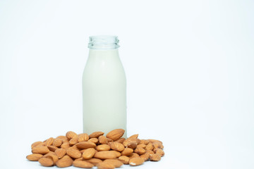 Bottle of almond milk and nuts on white background