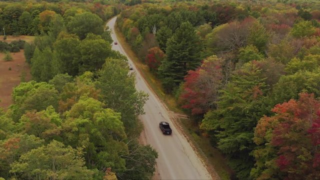 Pullback aerial shot of early fall colors along the road in northern Michigan.