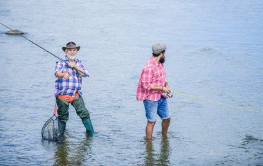 Male friendship. Father and son fishing. Summer weekend. Fishing together. Men stand in water....