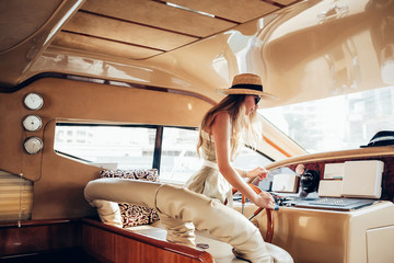 summer mood photo Beautiful blonde woman model in a hat and dress inside a yacht at the wheel