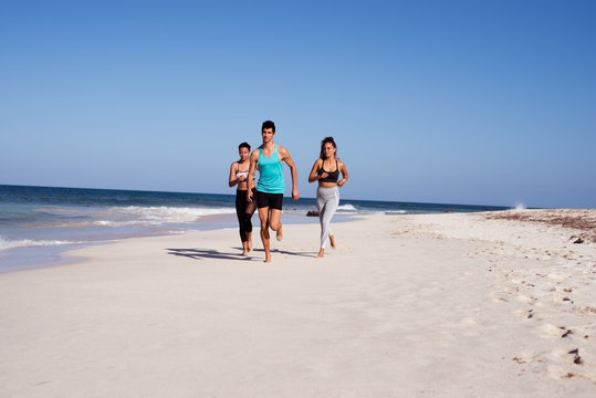 Three Young People Running On The Beach